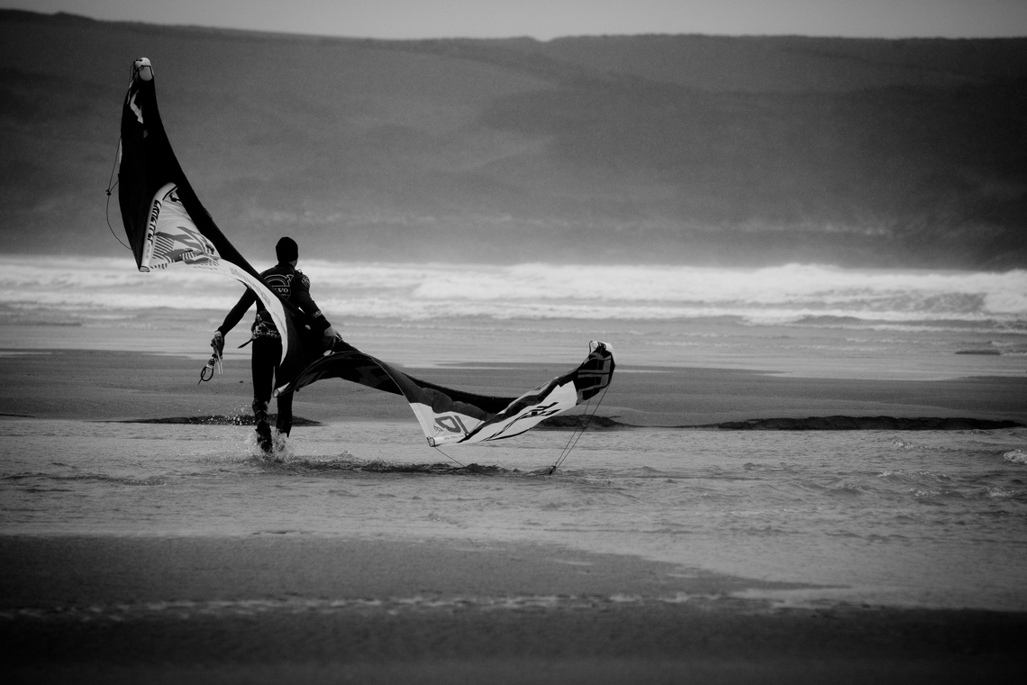 Kitesurfer walking on the beach with his kite.