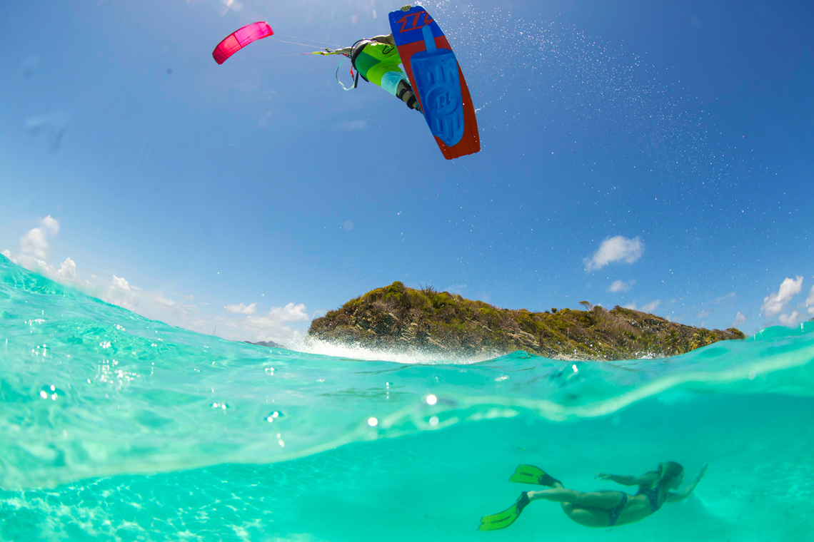The 2016 North Kiteboarding Rebel kite and Gambler board over tropical waters. Kiteboarder jumping while girl dives under water.